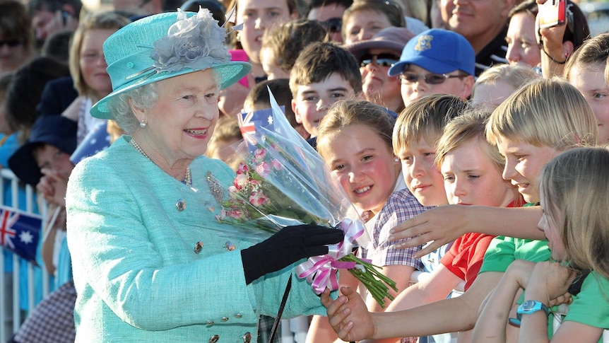 Queen Elizabeth II receives gifts from the crowd on arrival in Canberra on October 19, 2011.