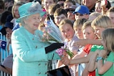 Queen Elizabeth II receives gifts from the crowd on arrival in Canberra on October 19, 2011.