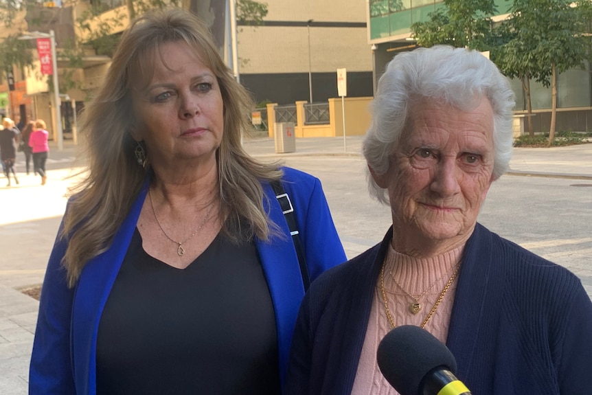 Two women stand on a street being interveiewed by a TV crew.