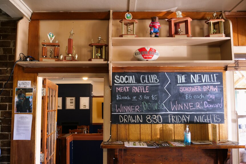 Inside of a pub with a blackboard, football and sport trophies.