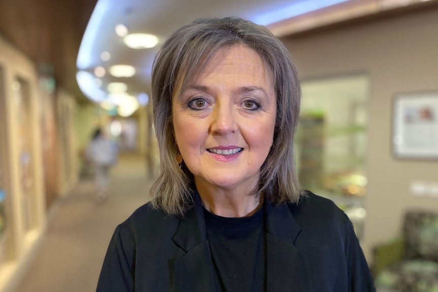 A woman with grey hair inside a curved hallway