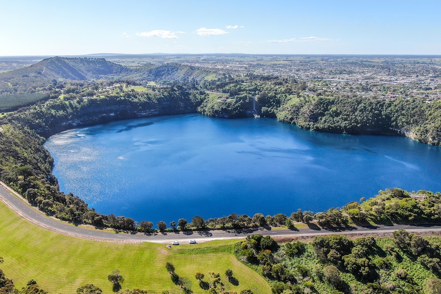 An aerial photo of a large deep blue lake surrounded by a ring road and adjoining farm properties.