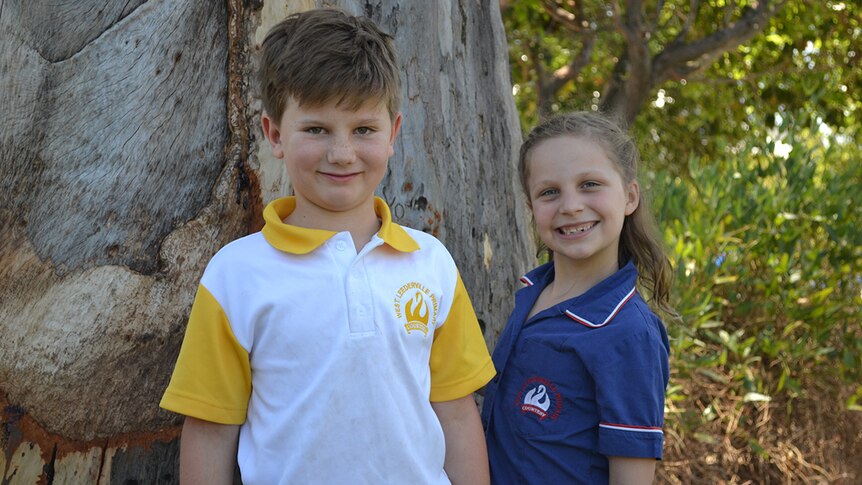 Colour photo of primary school students William and Sophie posing outdoors in front of a tree.