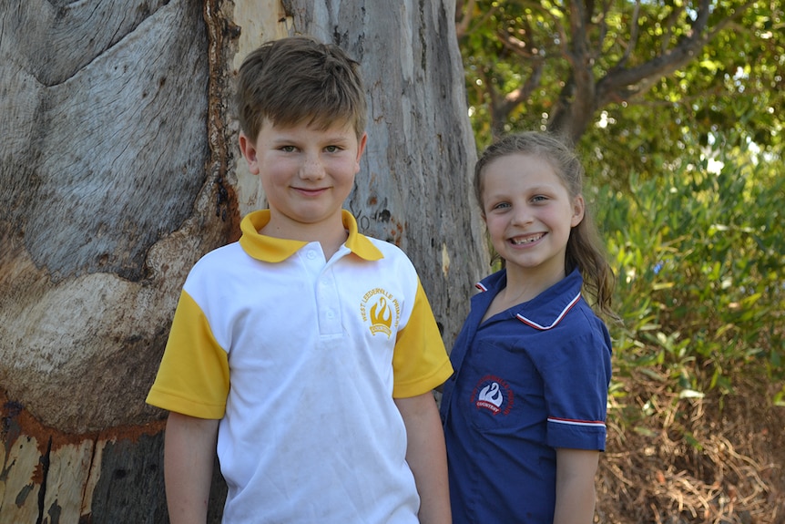 Colour photo of primary school students William and Sophie posing outdoors in front of a tree.