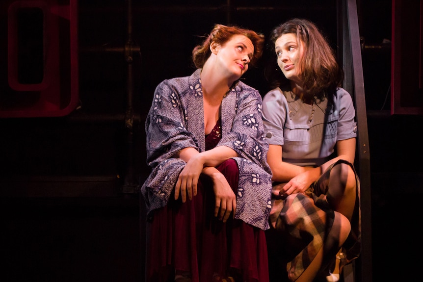 Bishanyia Vincent and Loren Hunter on stage, sitting on step looking at each other like love birds, wearing 1940s-era clothes.