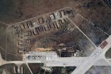 above-ground satellite image of an air base that appears to have been on fire, equipment looks damaged and nearby trees burnt