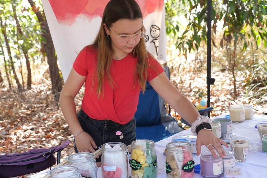 young girl with glasses in red, standing behind a table with candles.