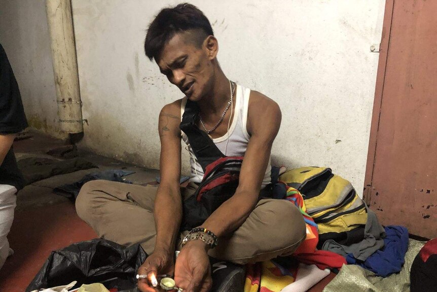 A man holds a cigarette lighter to his drugs prior to injecting.