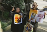 A woman and man hold pictures of Wubanchi Asfaw outside court.