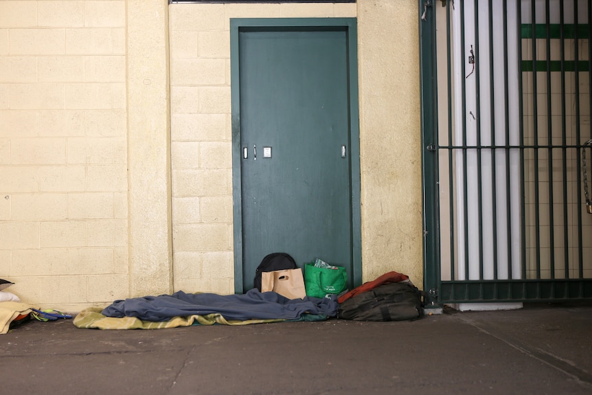 Blankets and bags of rough sleeper on the ground under shelter