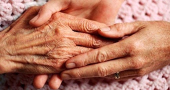 Elderly woman's hands  being held by another pair of hands.