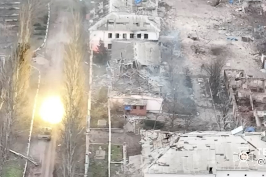A tank fires a round near heavily damaged buildings in Soledar.
