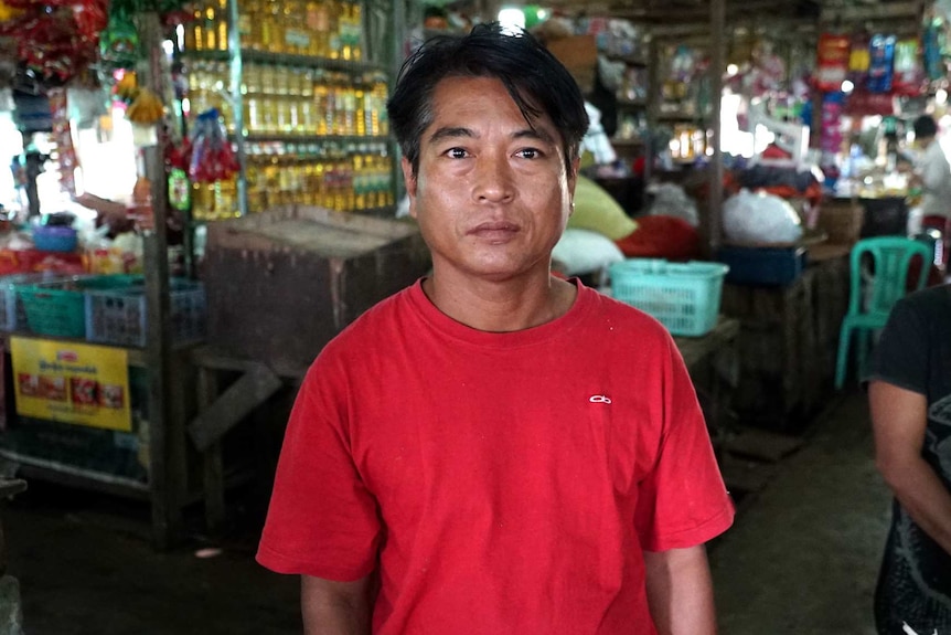 Aung Thu stands in the foreground of a busy enclosed market.
