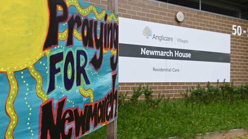 A colourful sign says "Praying FOR Newmarch" outside the front of Newmarch House.