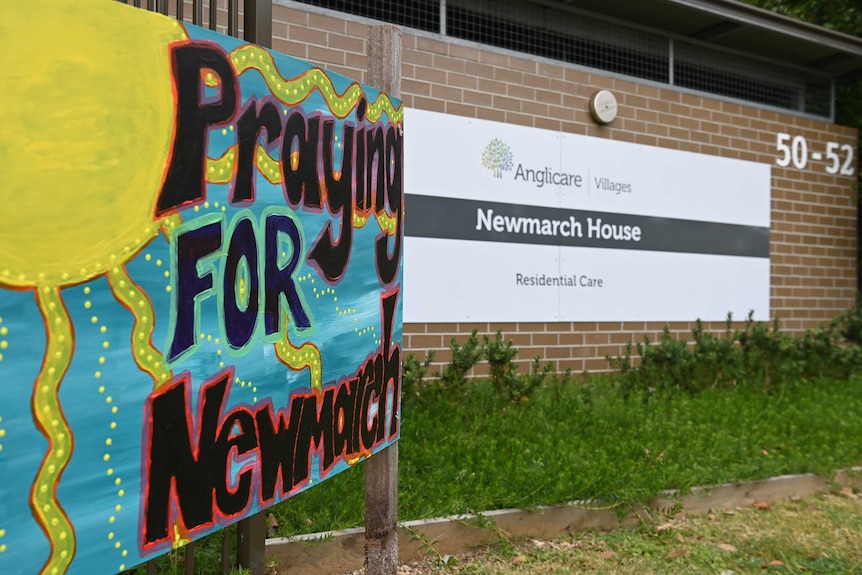 A colourful sign says "Praying FOR Newmarch" outside the front of Newmarch House.