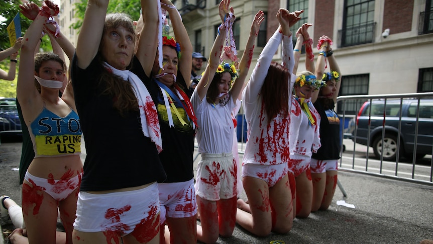 Women protest wearing white underwear with red paint to represent blood from sexual violence. 