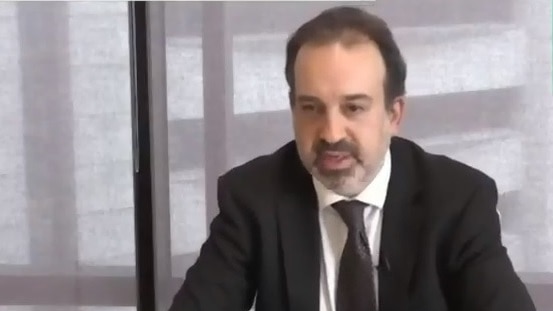 A screenshot of Mr Pakula wearing a suit and tie speaking via webcam. Auslan interpreter in top right screen.