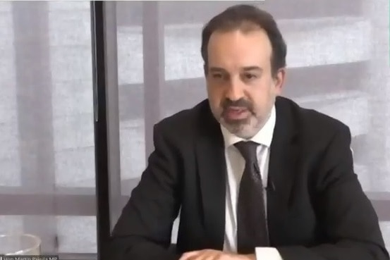 A screenshot of Mr Pakula wearing a suit and tie speaking via webcam. Auslan interpreter in top right screen.