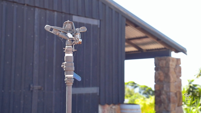 House with large water sprinkler in the foreground