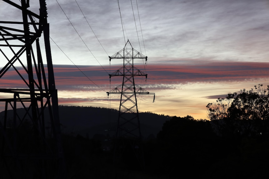 Silhouette of an electricity transmission tower at dawn.