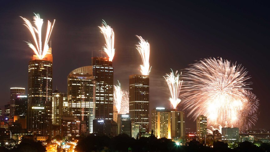 Fireworks explode on the rooftops of buildings in the city during early New Year's Eve celebrations.