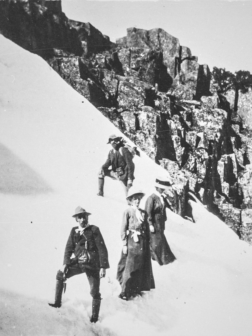 Edwardian bushwalkers walking over snow on a mountain in Tasmania, black and white.