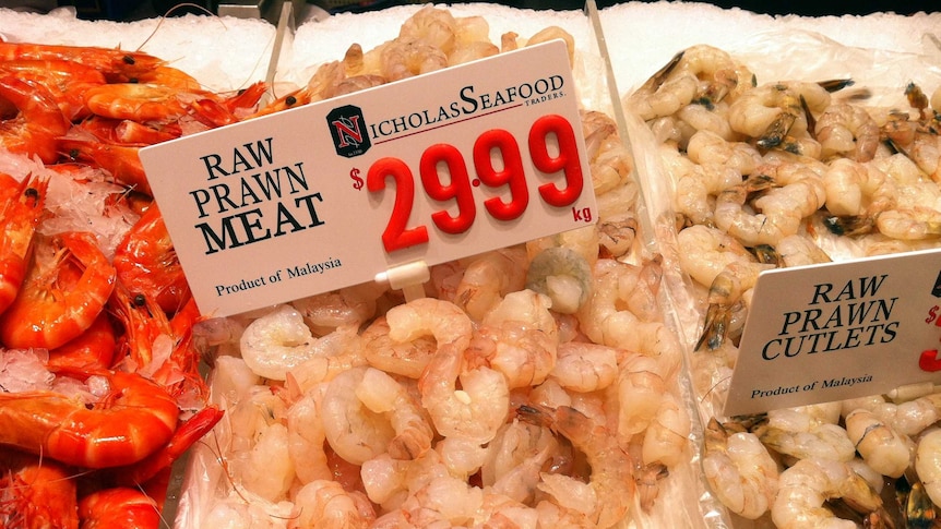 Raw prawns on a tray in a supermarket deli.