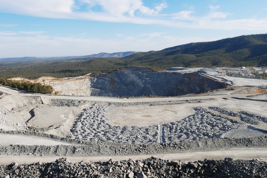 a open gold mine with white dirt and rocked against a mountain landscape
