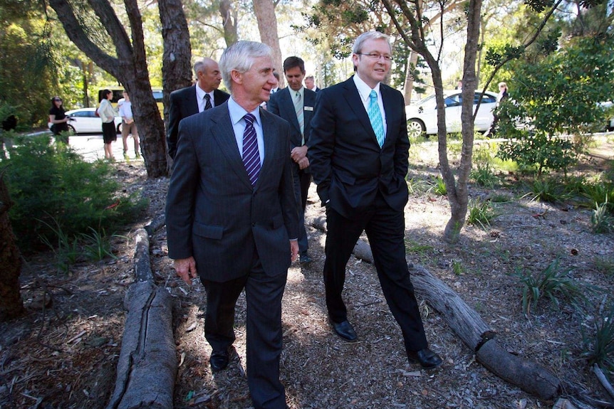A wide shot showing John Kobelke and Kevin Rudd walking through the Botanical Gardens in Perth with other men behind them.