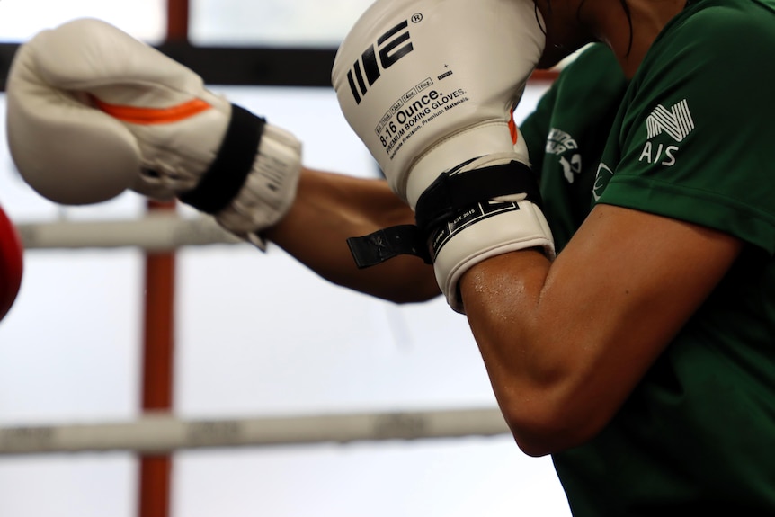 拳击手在拳击场上对打时戴着白色拳击手套的特写镜头。