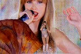 Taylor Swift against the backdrop of herself on screen 