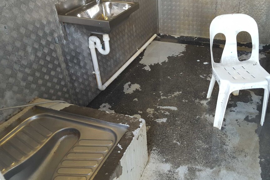 A toilet and sink in a steel room on Manus Island.