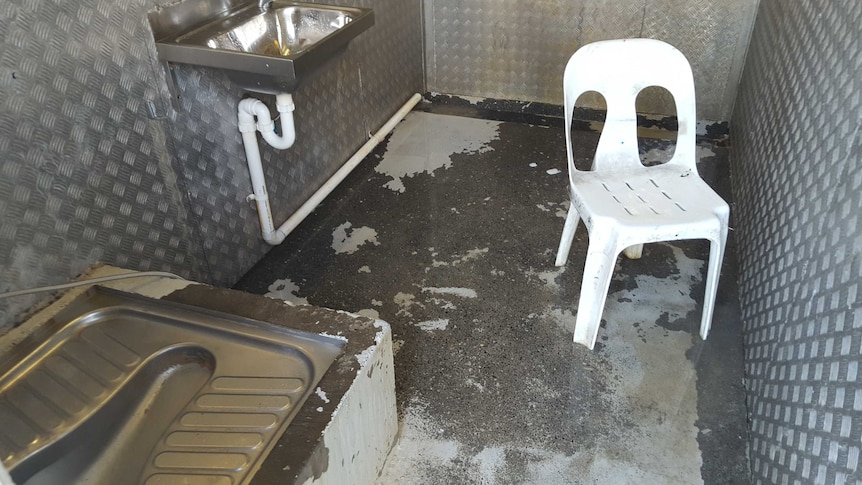 A toilet and sink in a steel room on Manus Island.