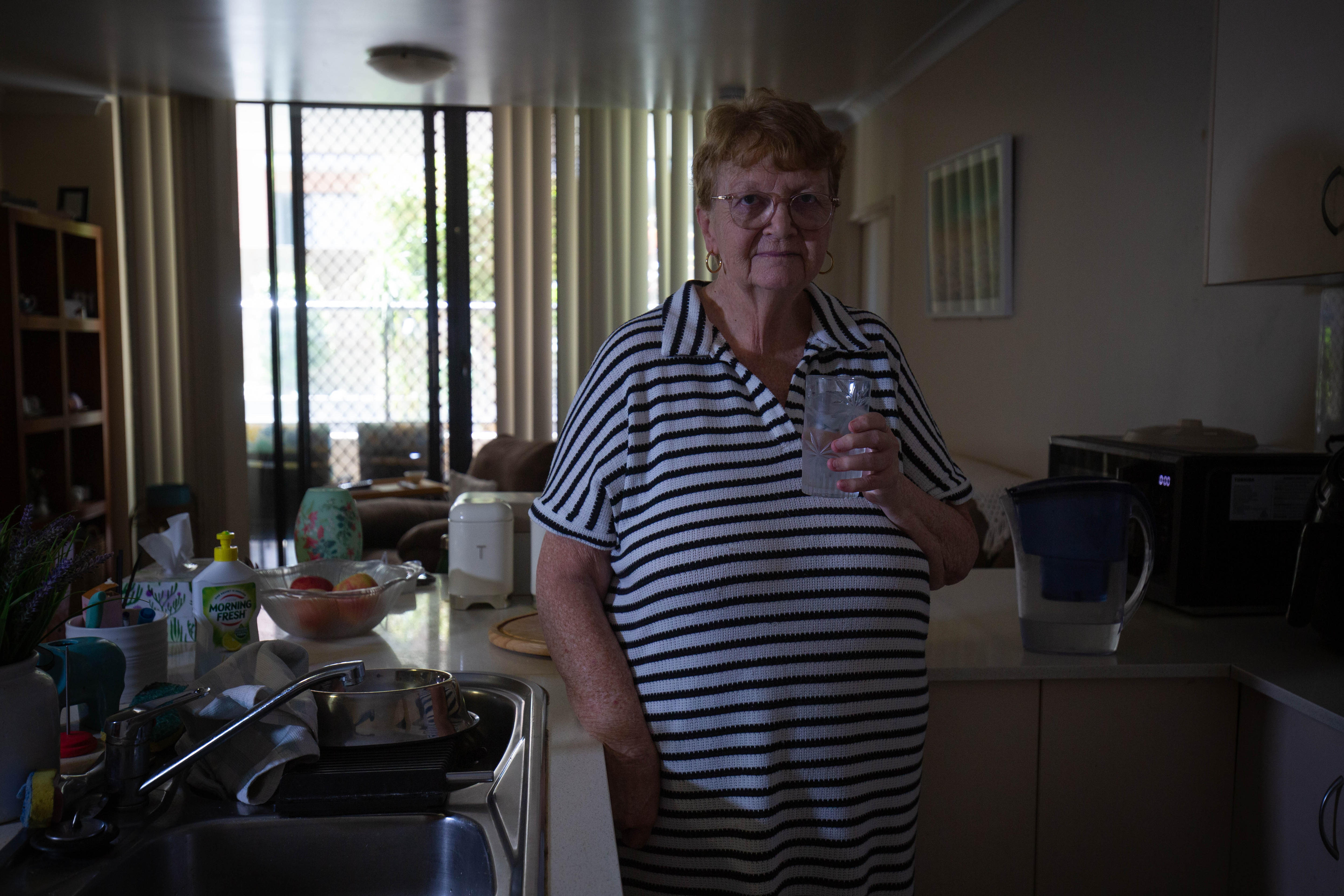 Uma mulher segura um copo na cozinha.