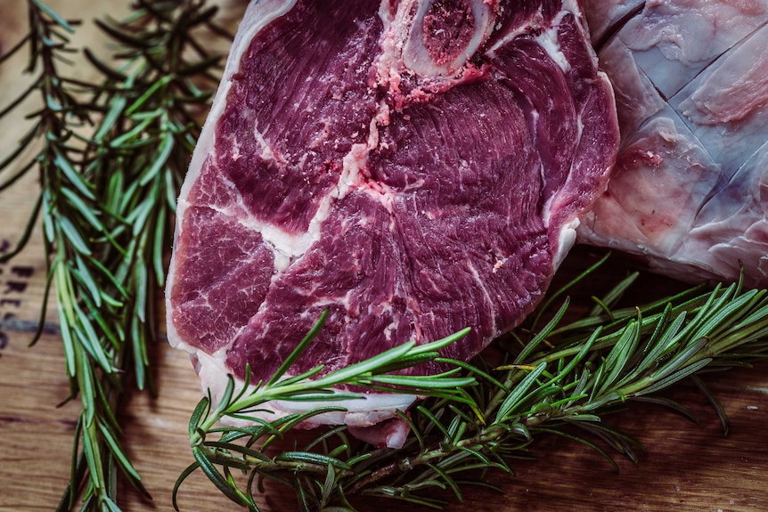A raw cut of steak with rosemary next to it