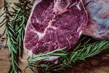 A raw cut of steak with rosemary next to it