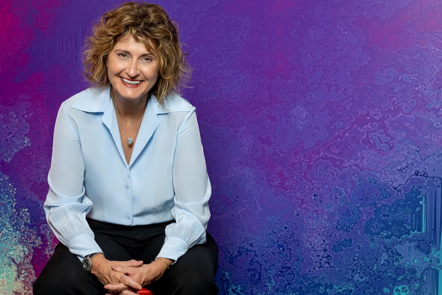 An image of Tracy Adams in front of a purple screen 