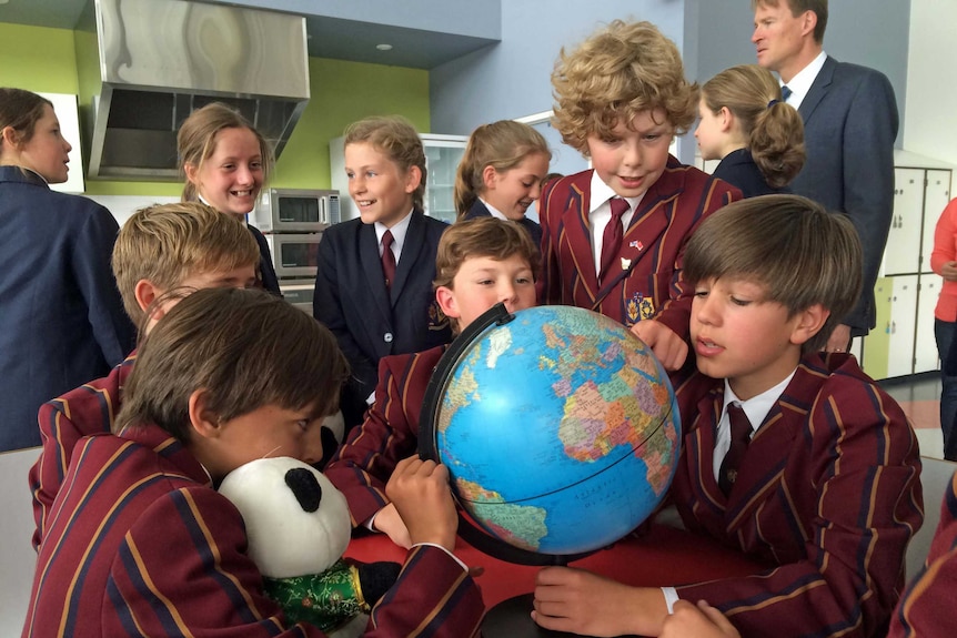 Grade 6 students from Scotch Oakburn College look at a globe of the world.