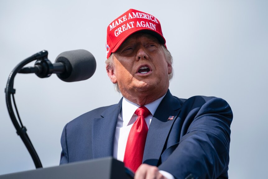 President Donald Trump speaks at a campaign rally while wearing a Make America Great Again hat