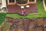 Two people survey the erosion of the land near the coast