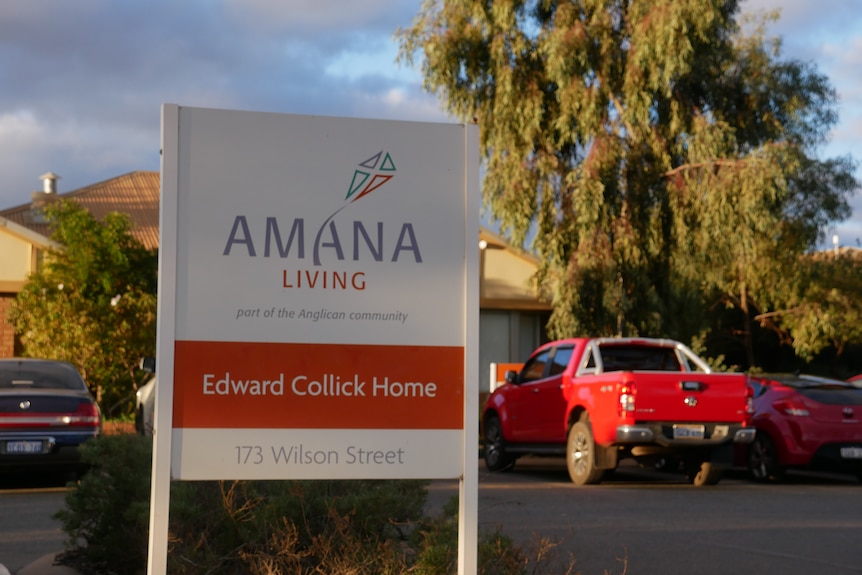 An Amana Living sign sits in the foreground of the photo, with cars in the background.