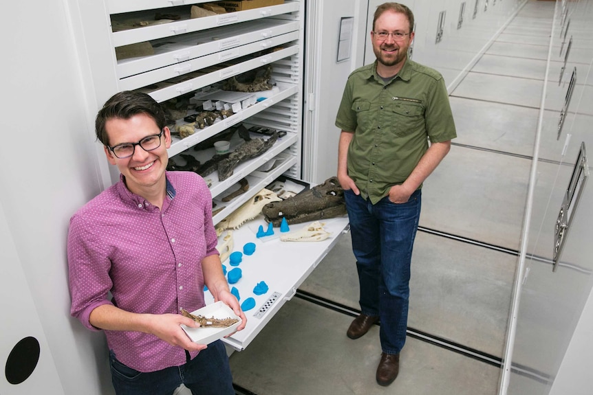 Two smiling people with a draw of croc skulls