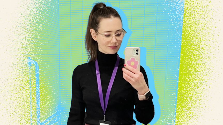A woman wearing glasses with a brown high ponytail takes a selfie in a mirror, half smiling.