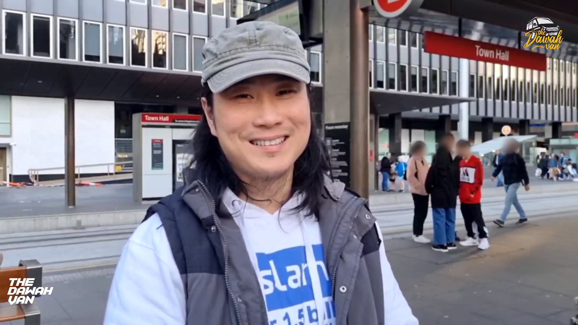 A man in a cap, long-sleeve top and vest smiles for a photo in Sydney's CBD.