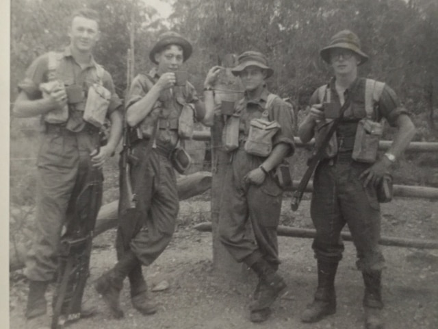 Black and white photo of four young soldiers drinking cups of tea