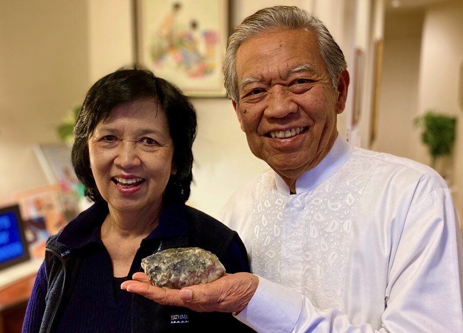 Man holding a rock standing next to a woman, both are smiling.