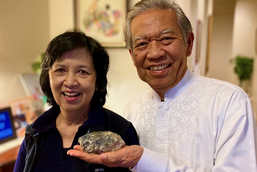 Man holding a rock standing next to a woman, both are smiling.