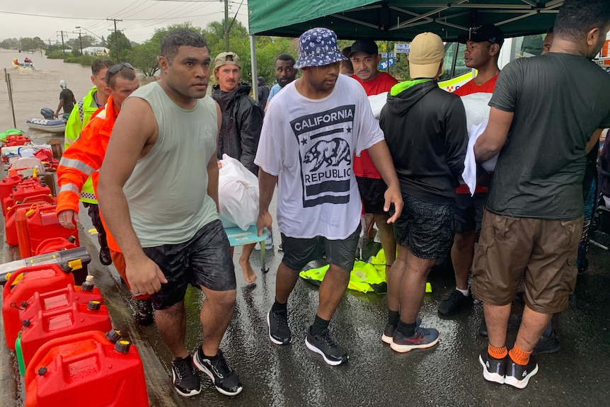 men carrying supplies amid floodwaters