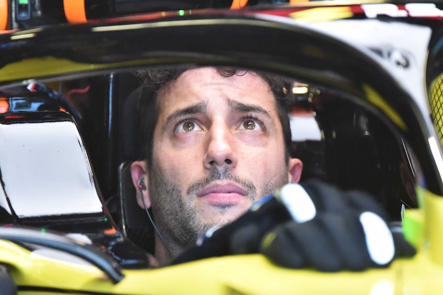 Daniel Ricciardo looks concerned as he looks up at something while sat in his Formula 1 car.