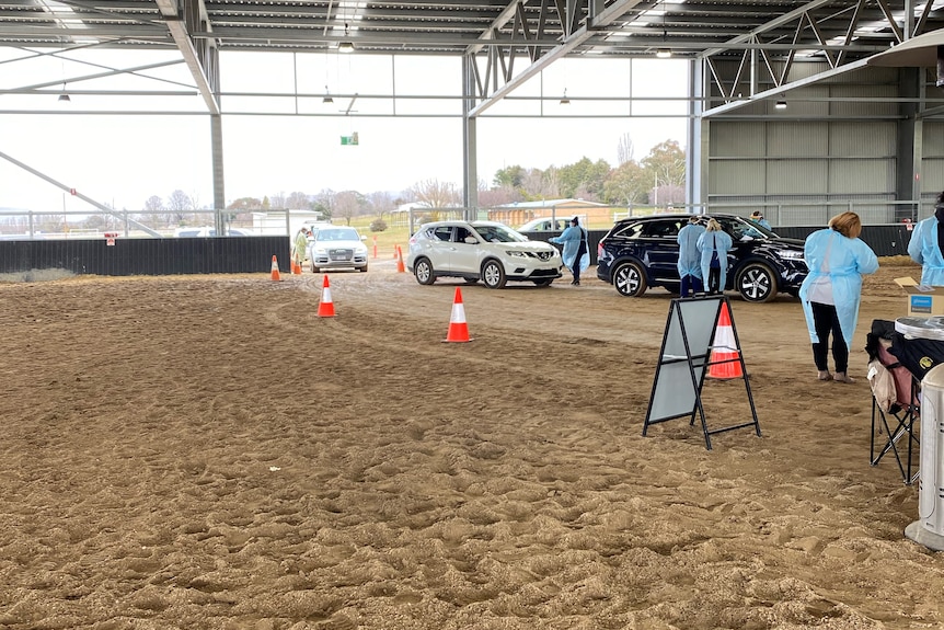 a line of cars at a shed waiting to get coronavirus swabs